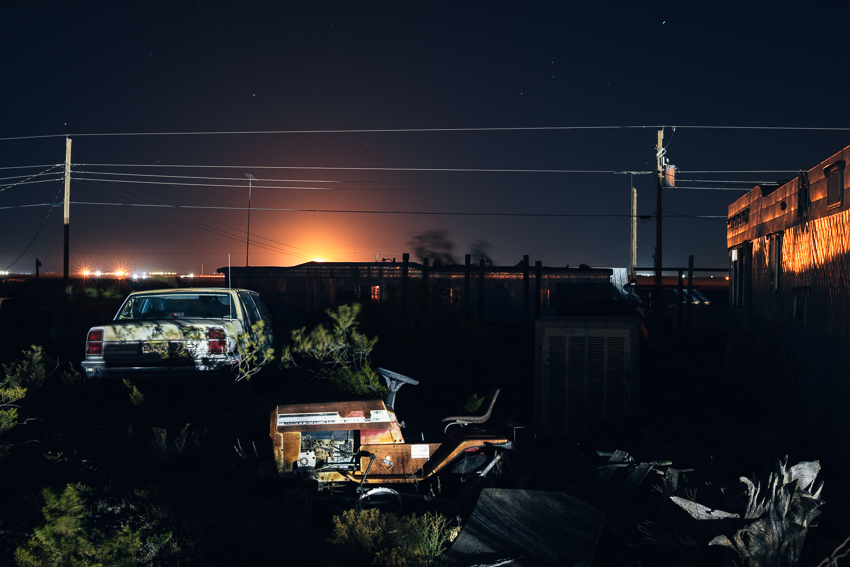 Abandoned camp outside Orla, Texas, lit up by a gas flare and saltwater disposal facility.
