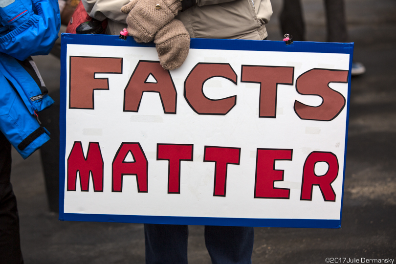 A protester holds a sign reading 'Facts matter.'