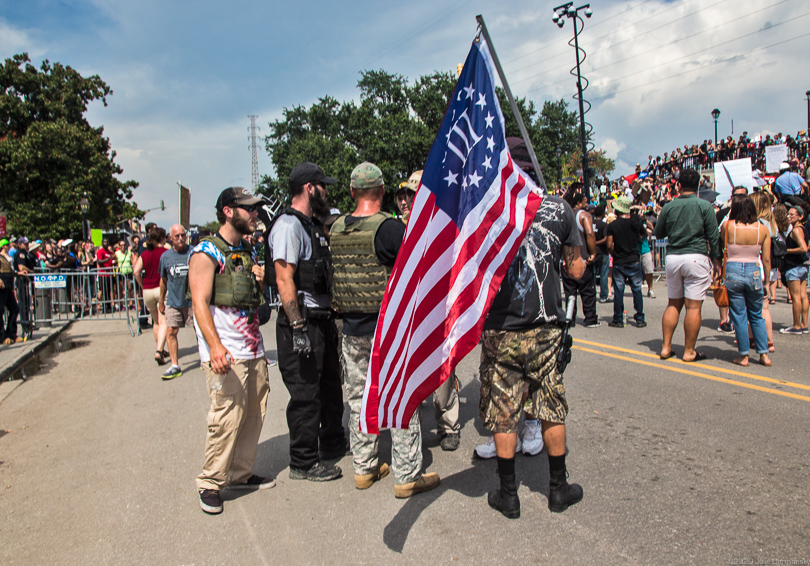 Protesters in military gear and holding a Three Percenter flag at a rally for a Confederate memorial in Louisiana