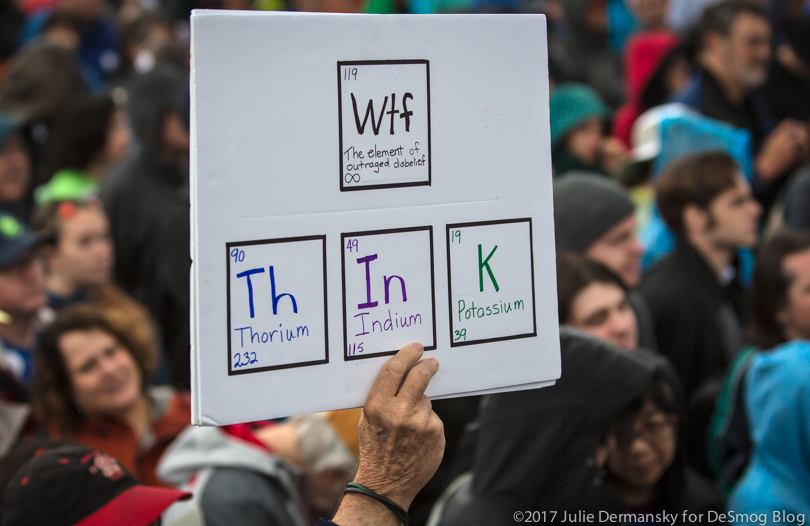 Person holding a March for Science sign drawing on the Periodic Table and calling for people to "think."