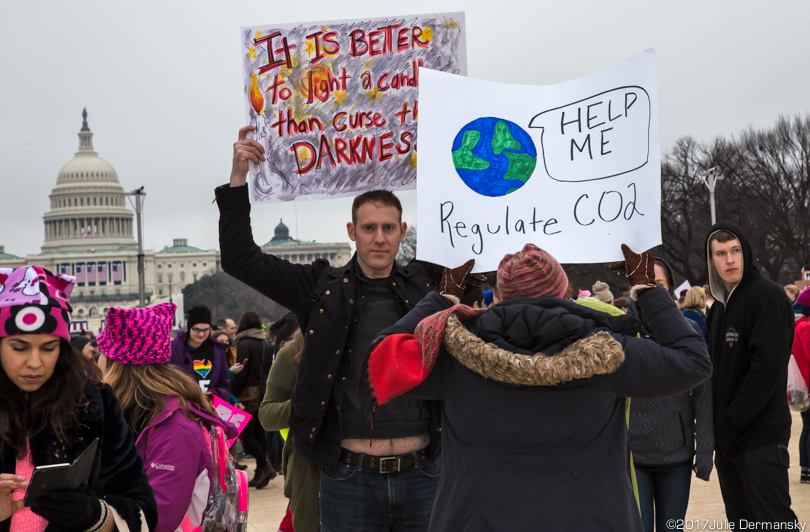 Marchers hold signs on the National Mall, including one calling for regulating carbon dioxide
