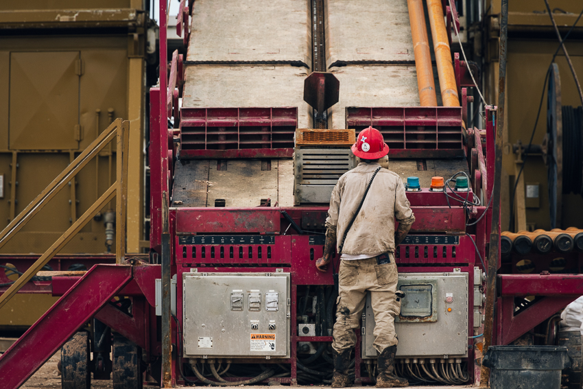 A roughneck in a red hard hat operates the pipe ramp on the oil rig Citadel Rig 6.