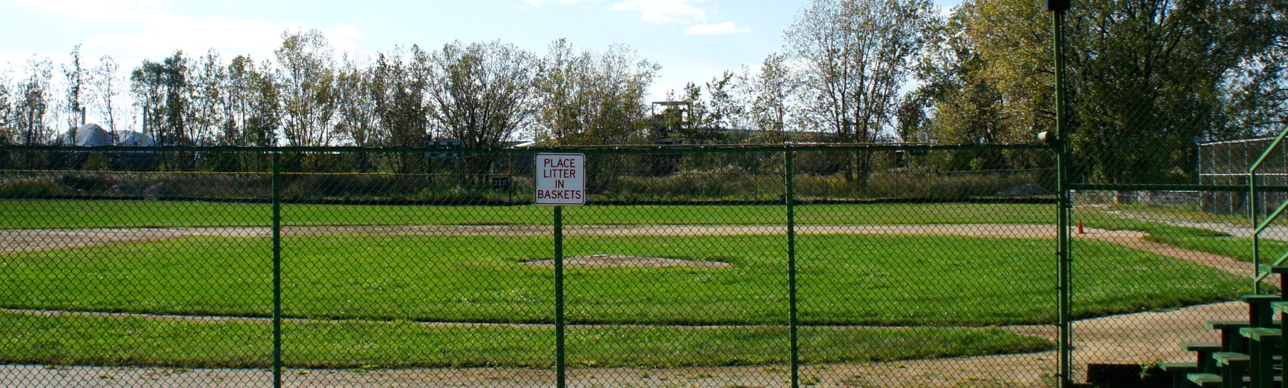 Hulking hills of pet coke loom behind this baseball field, where a little league game was cancelled last year after strong winds covered players and their families in pet coke dust.