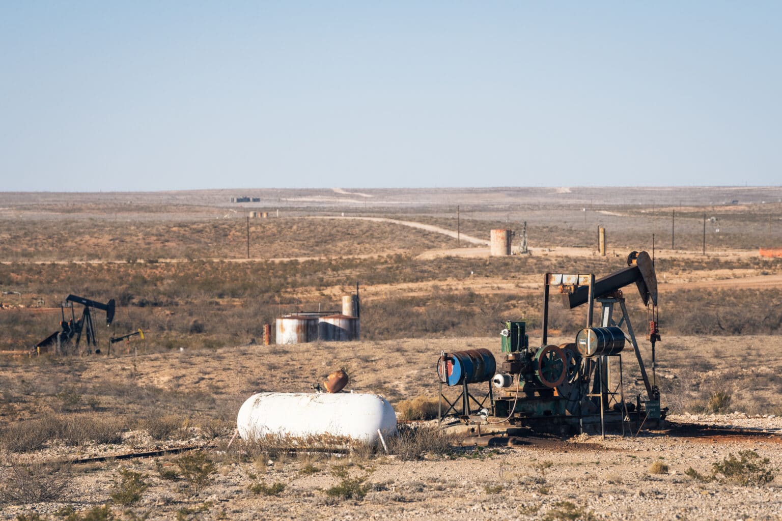 Several old pumpjacks dot the dry flat landscape of the Permian Basin