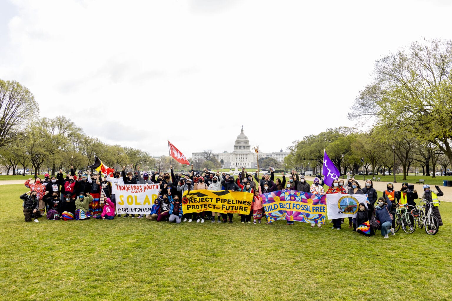 Indigenous youth holding signs protesting Line 3 and Dakota Access pipelines on the lawn in front of the U.S. Capitol