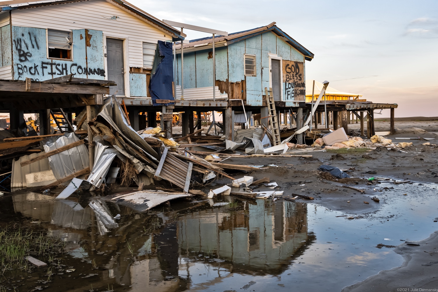 Damaged fishing camp houses and floodwaters at sunset