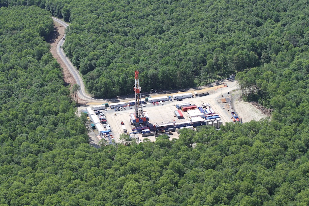 Gas drilling rig in the middle of a rectangular cut out in green forest