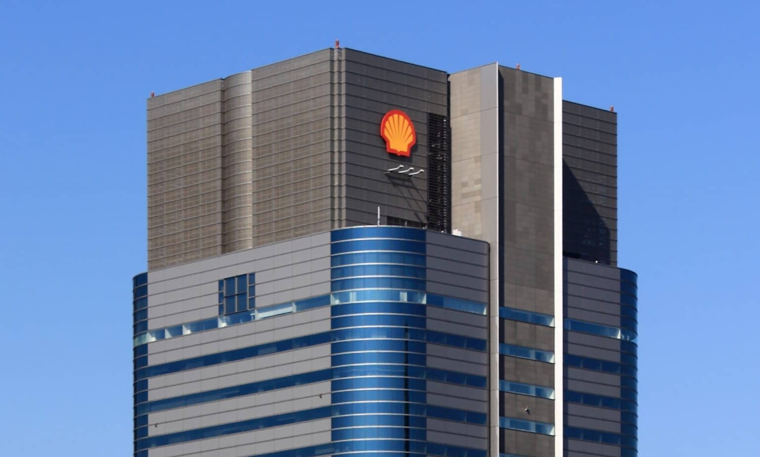 Top of a gray and blue skyscraper with yellow and red shell-shaped Shell oil logo