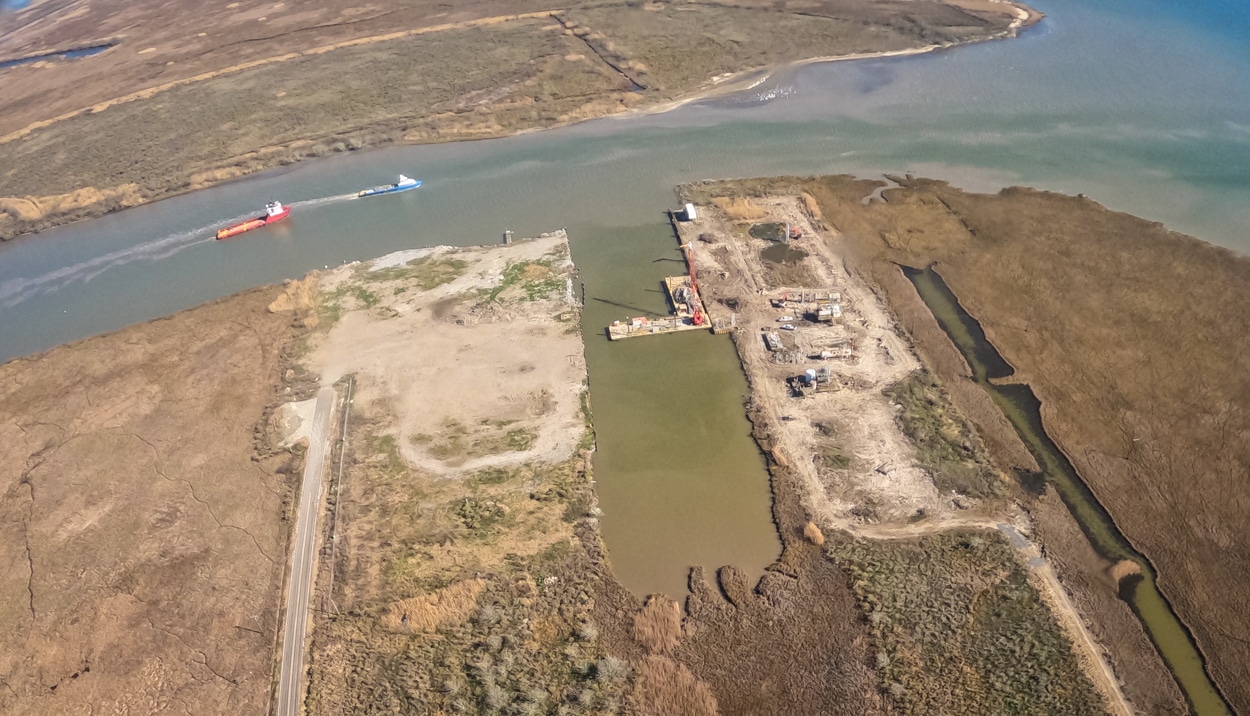 Aerial view of a bayou and canals on the Gulf of Mexico, with a wastewater injection well. Two barges float by