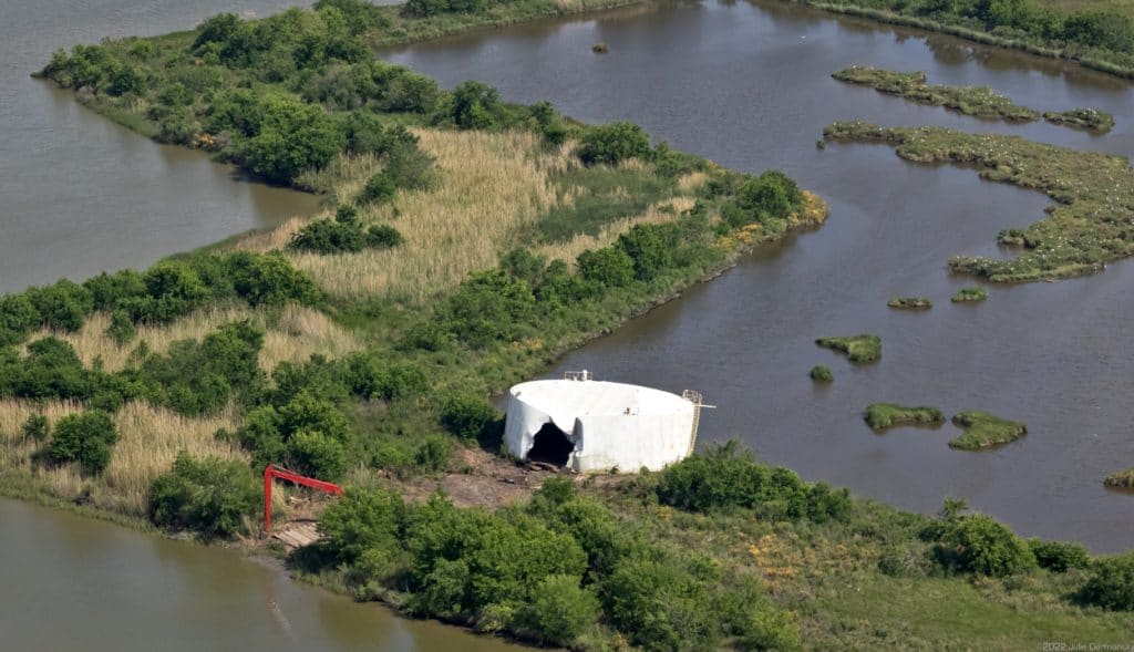 Damaged white storage tank blown off the Freshwater City disposal well site next to Freshwater Bayou.