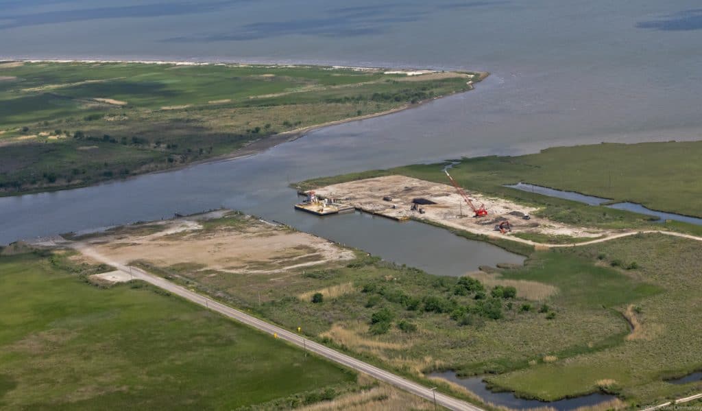 Saltwater injection well site in cleared dirt patch along the coast.