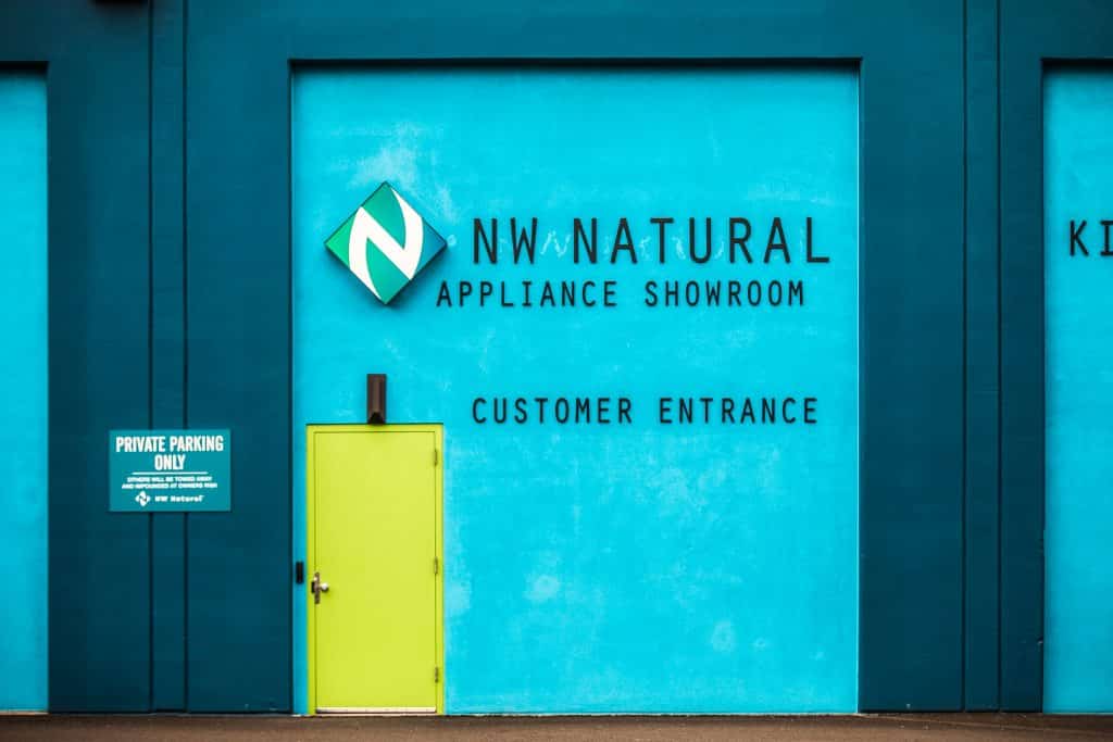 Turquoise exterior entrance with lime green door and 'NW Natural appliance showroom customer entrance' sign