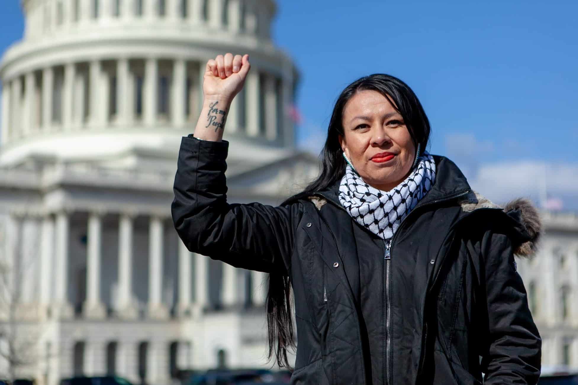 A woman raising a fist in protest in front of the U.S. Capitol
