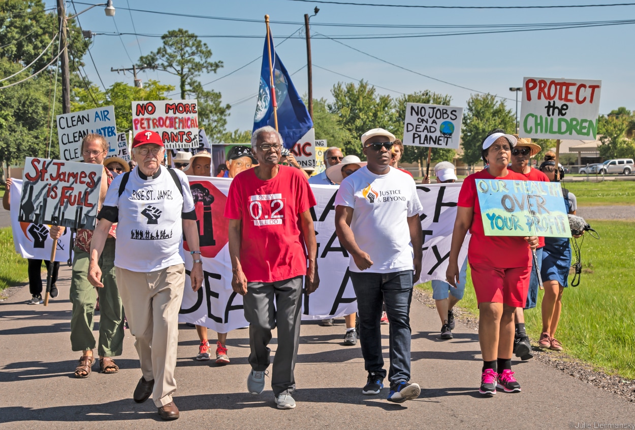 Three men and a women lead a march with banners, flags, and signs