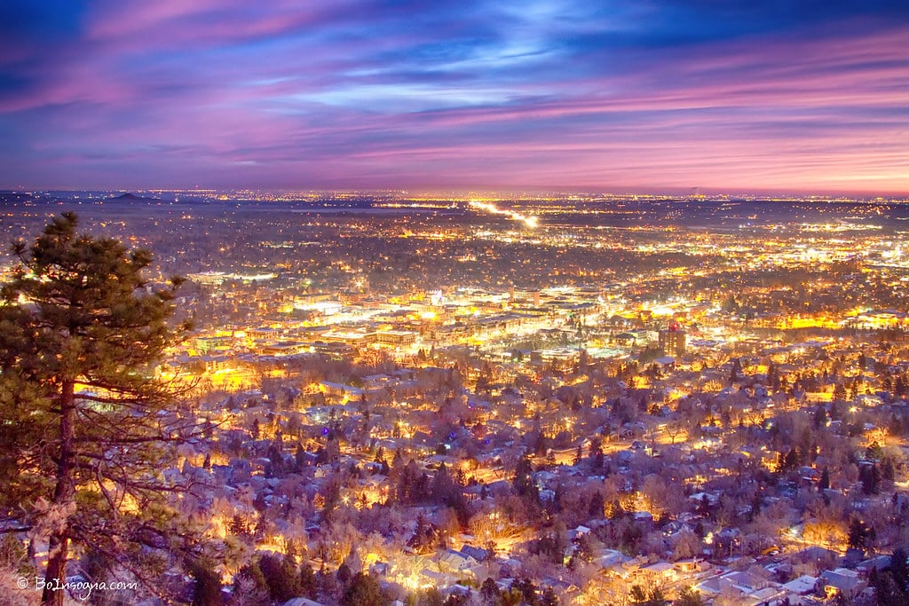 Aerial view of downtown Boulder Colorado at dawn with city lights glowing against sunrise