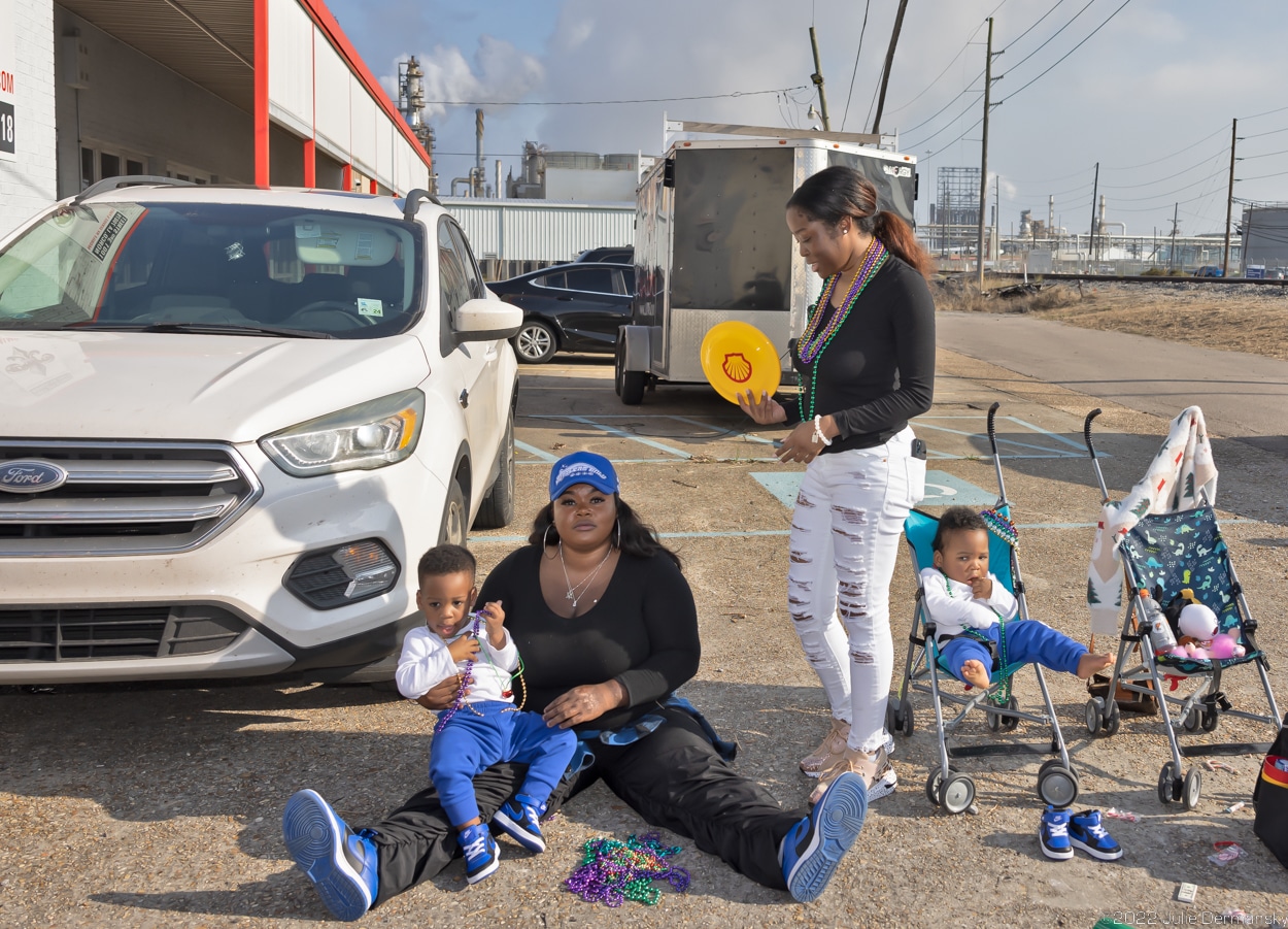 two women and two children outside in Norco, Louisiana, fan themselves with a Shell-branded frisbee