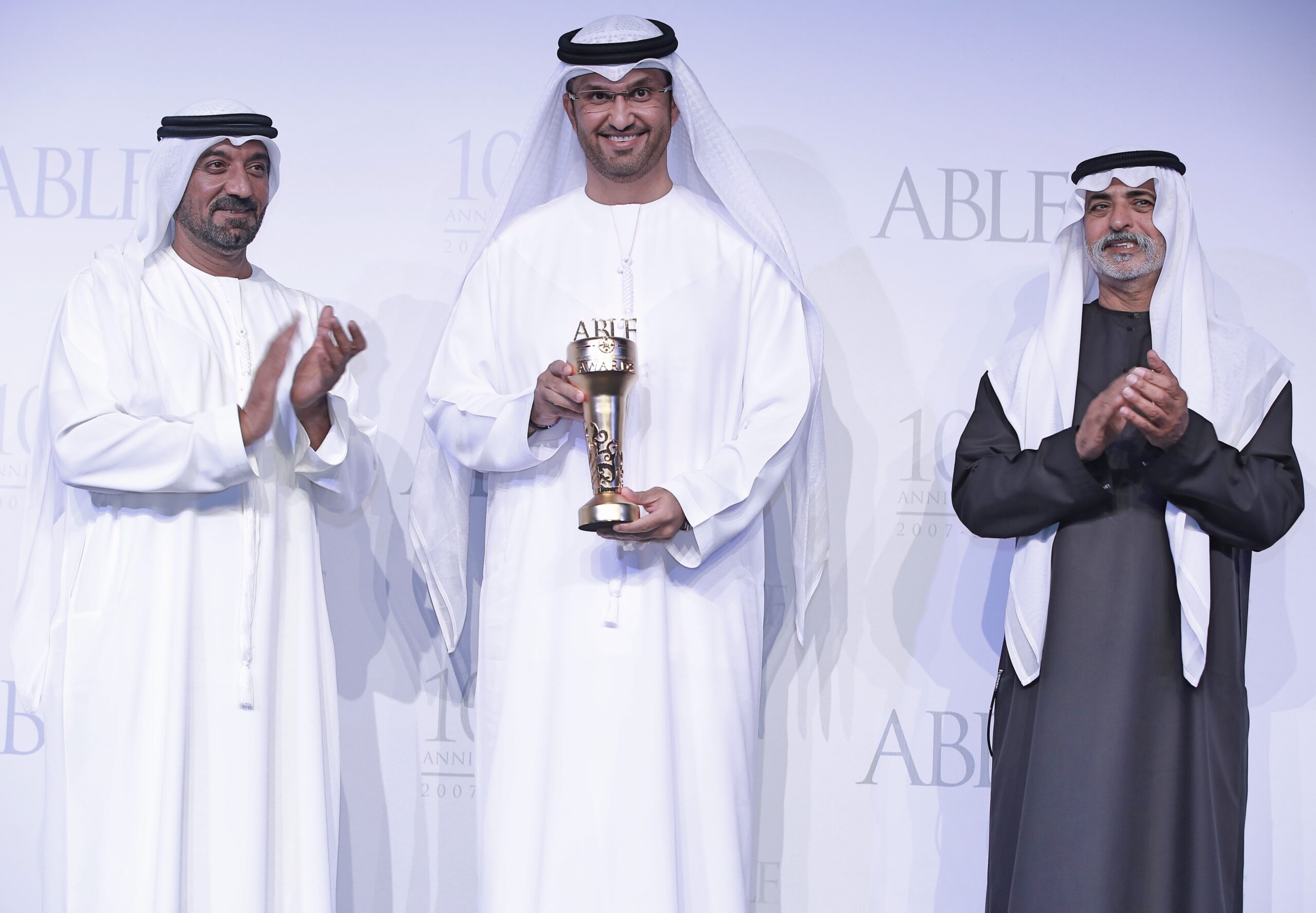 Three men stand shoulder to shoulder during an award ceremony