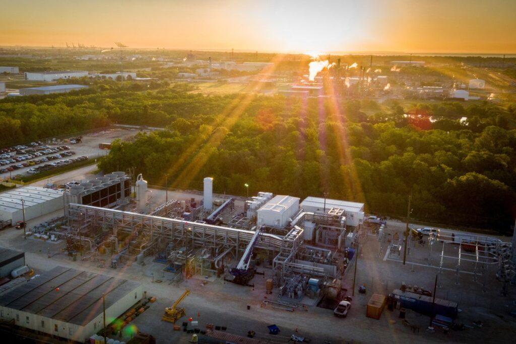 Sun glinting over the flat horizon and an industrial facility