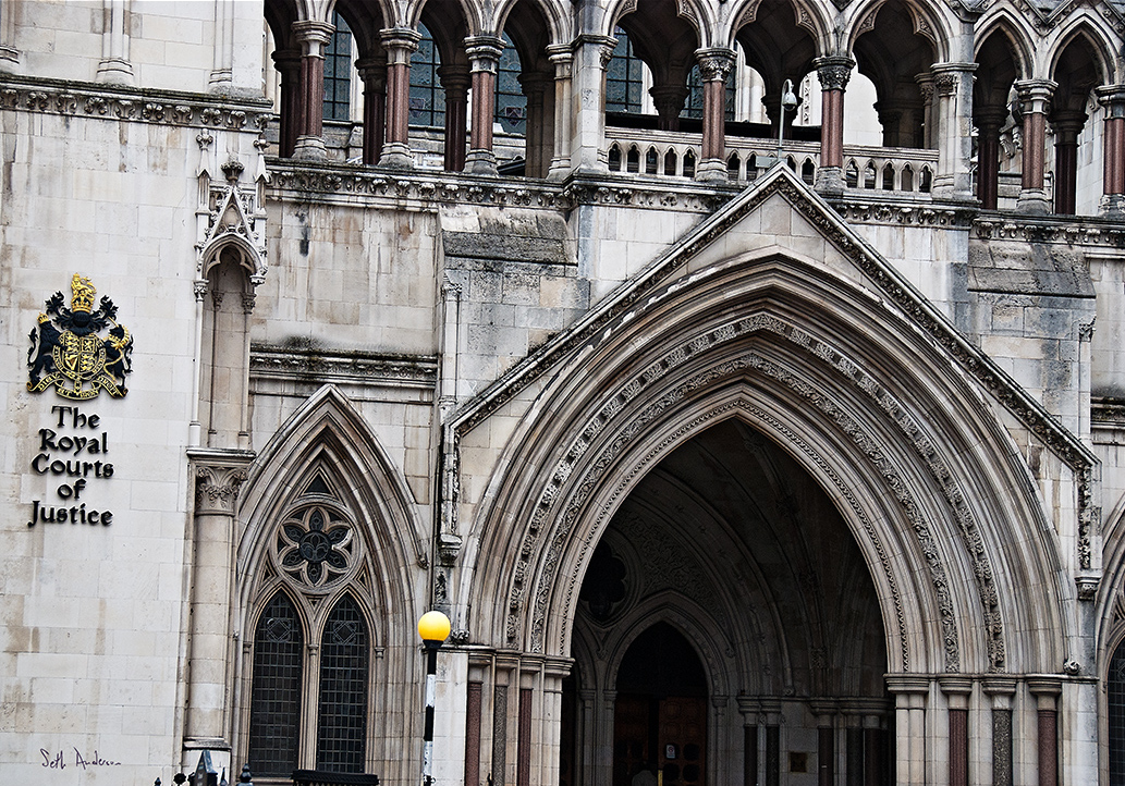 Exterior view of the Victorian Gothic arched doorways and windows of the pale stone Royal Courts of Justice building