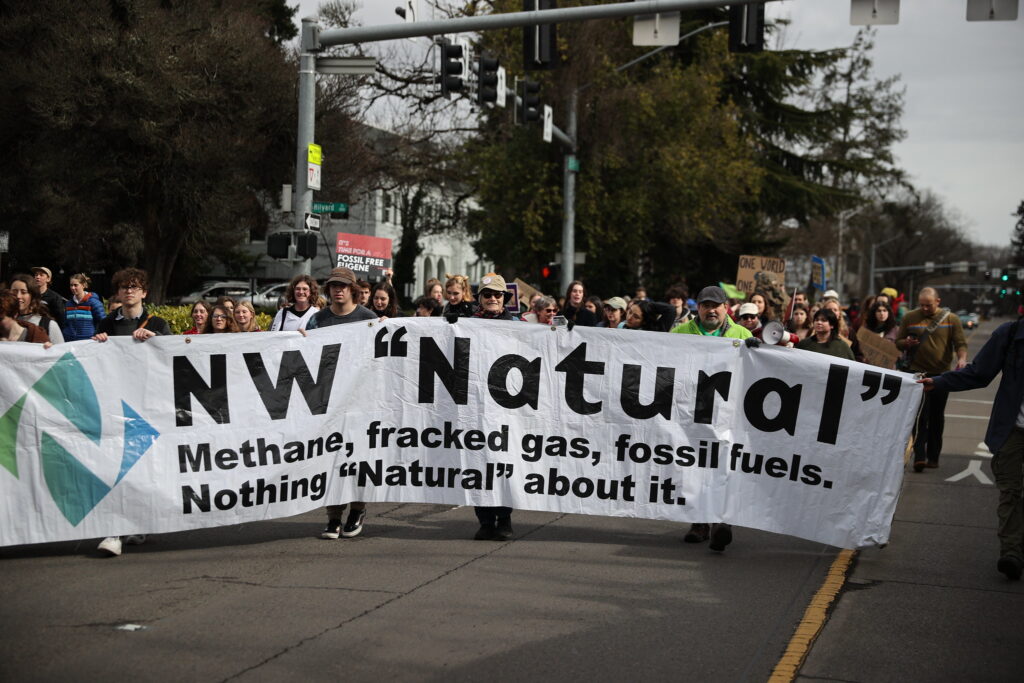 Marchers in Eugene Oregon carrying banner that reads, NW "Natural" methane fracked gas, fossil fuels. Nothing "natural about it."
