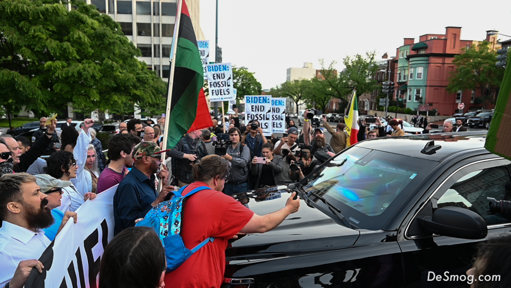 A driver of a black SUV with police lights attempted to push their way through the Climate Defiance blockade line of activists holding flags and signs.