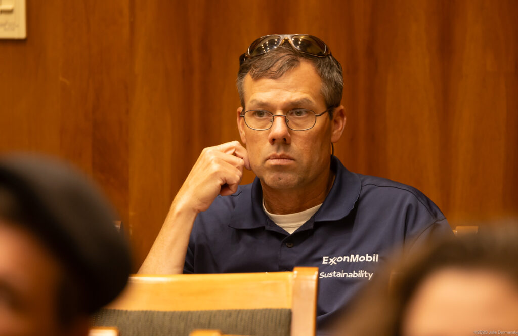 A man with glasses and a blue polo shirt embossed with 'ExxonMobil Sustainability.'