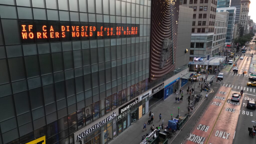 Climate clock ticker on side of a NYC skyscraper lit up with the message "if ca divested from oil and gas workers would be .6 billion richer"