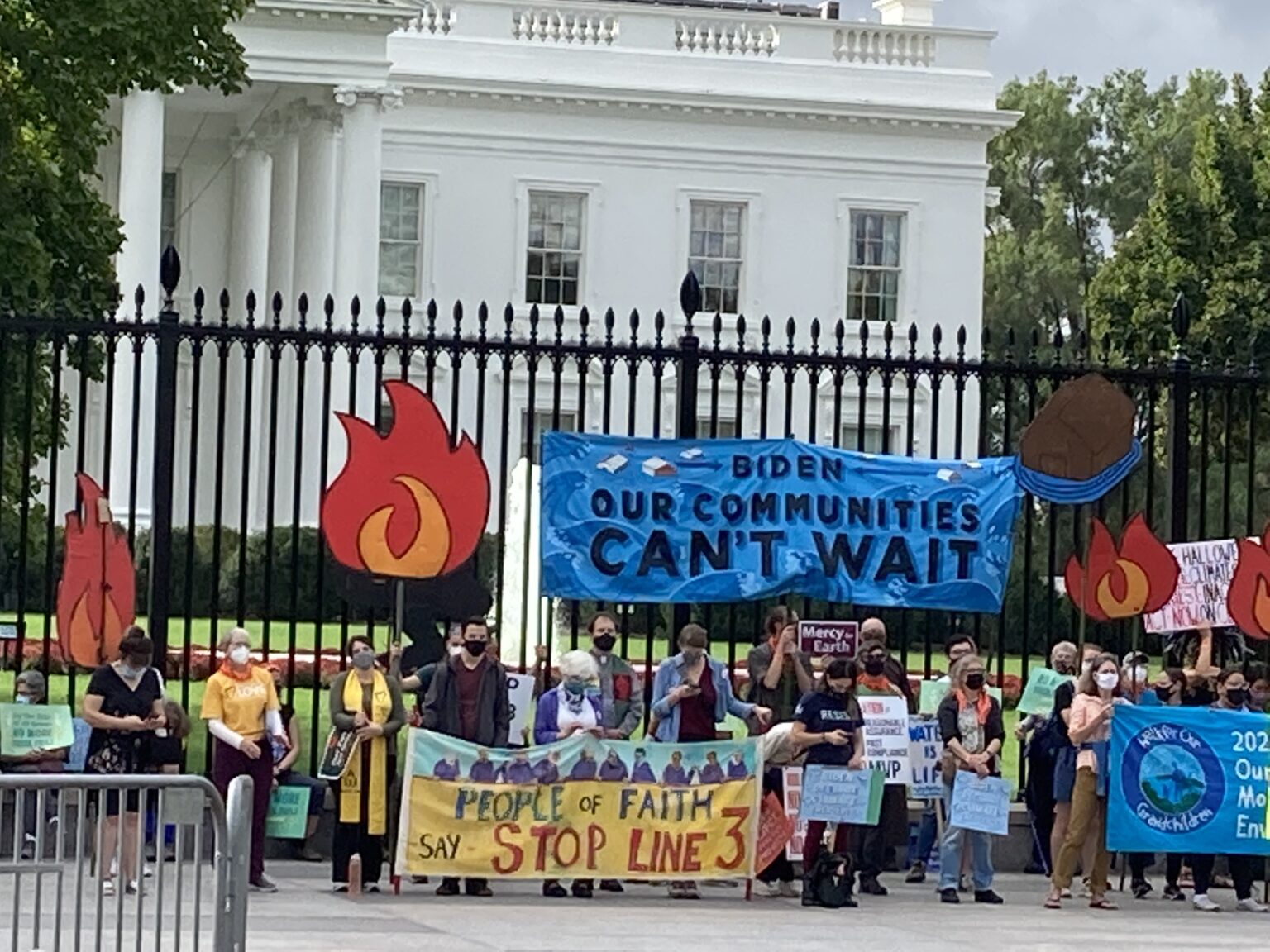 Climate activists in front of White House fence holding sign reading, Our Communities Can't Wait
