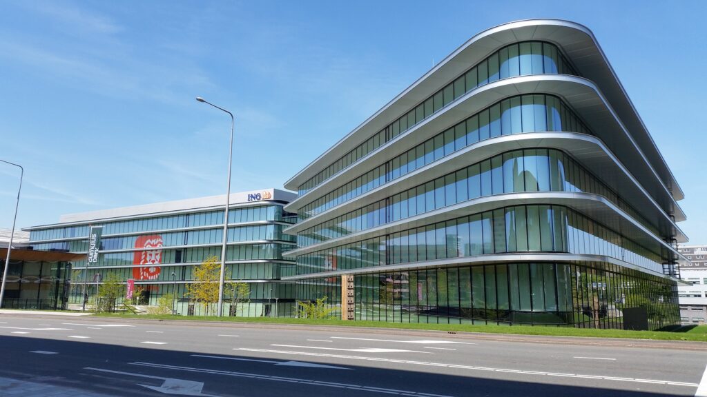 A glass and steel five-story office building with ING logo on top and orange lion graphic across the windows' side.