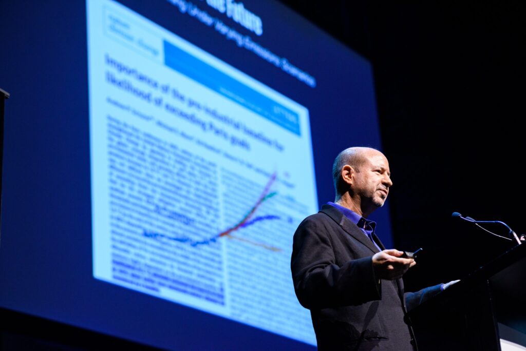 Scientist Michael Mann presenting in front of a projection of the famous hockey stick graph of rising global temperatures.