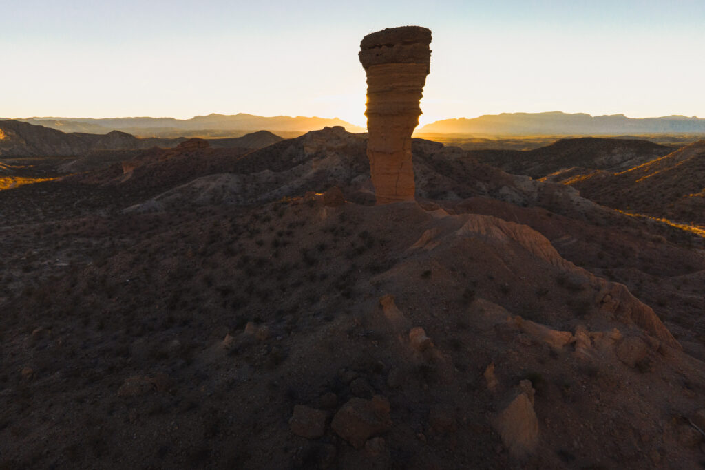 A sandstone column silhouetted by the rising sun over the desert of west Texas.