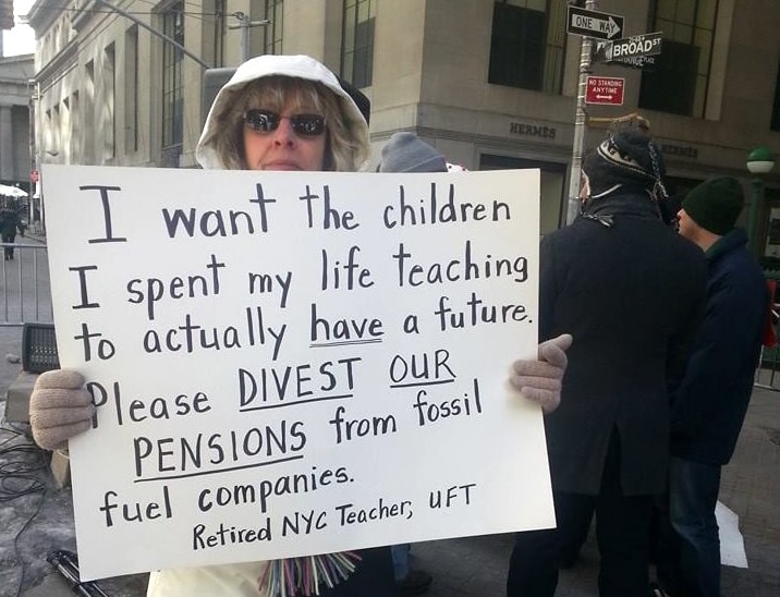 Woman holding protest sign that reads, i want the children i spent my life teaching to actually have a future. please divest our pensions from fossil fuel companies - retired nyc teacher, uft