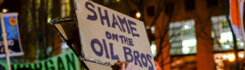 Shame Oil Bros on cardboard sign