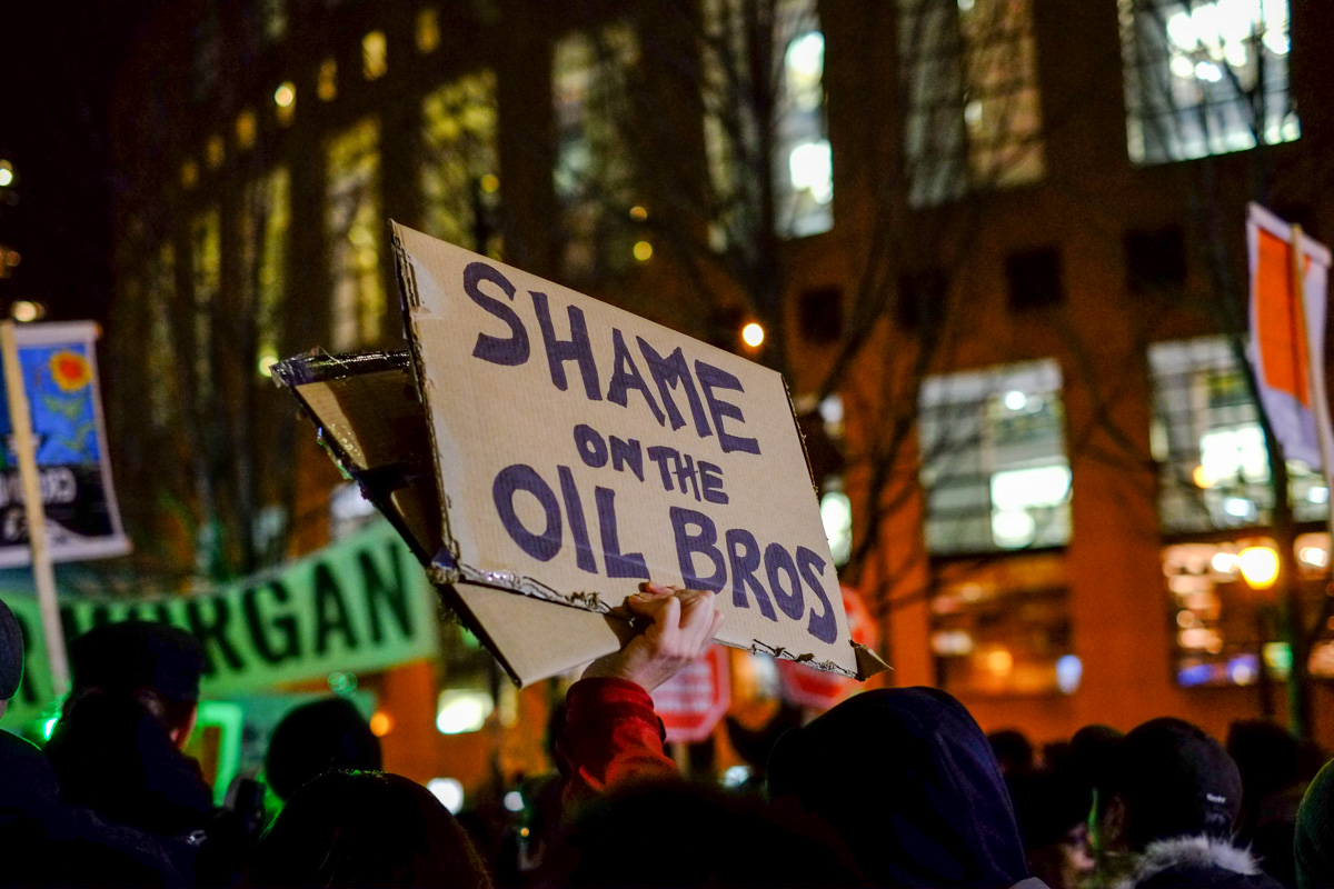 Shame Oil Bros on cardboard sign