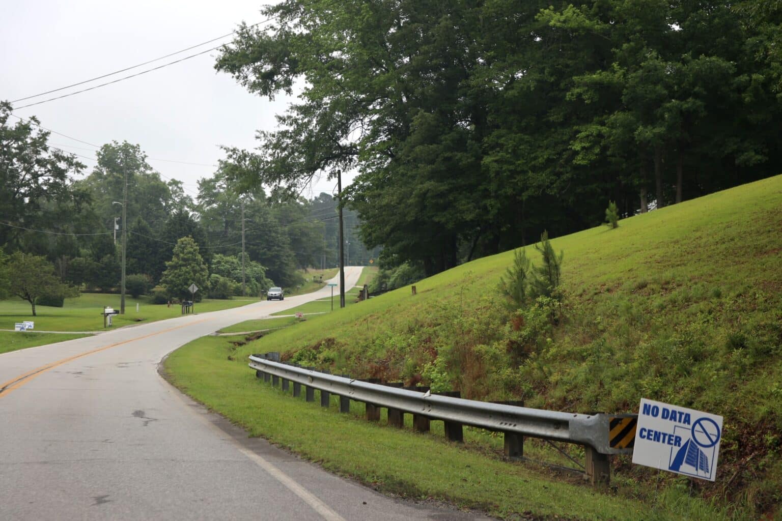 A paved two lane road through a rural residential area in Coweta County Georgia USA. Lawns and mailboxes are visible along the left side of the road.