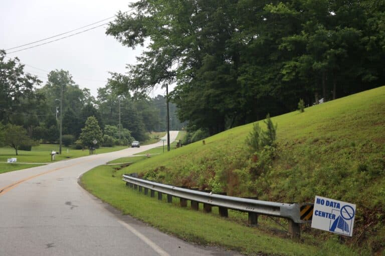 A paved two lane road through a rural residential area in Coweta County Georgia USA. Lawns and mailboxes are visible along the left side of the road.