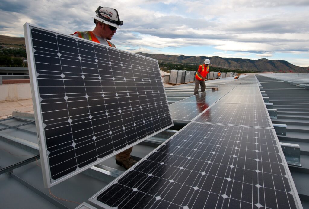 Two construction workers install solar panels.