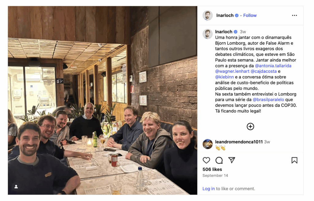 Photograph of a group of six men and one woman sitting around three tables pushed together at a restaurant, perhaps a diner. They are dressed in casual clothing, looking at the camera and smiling.