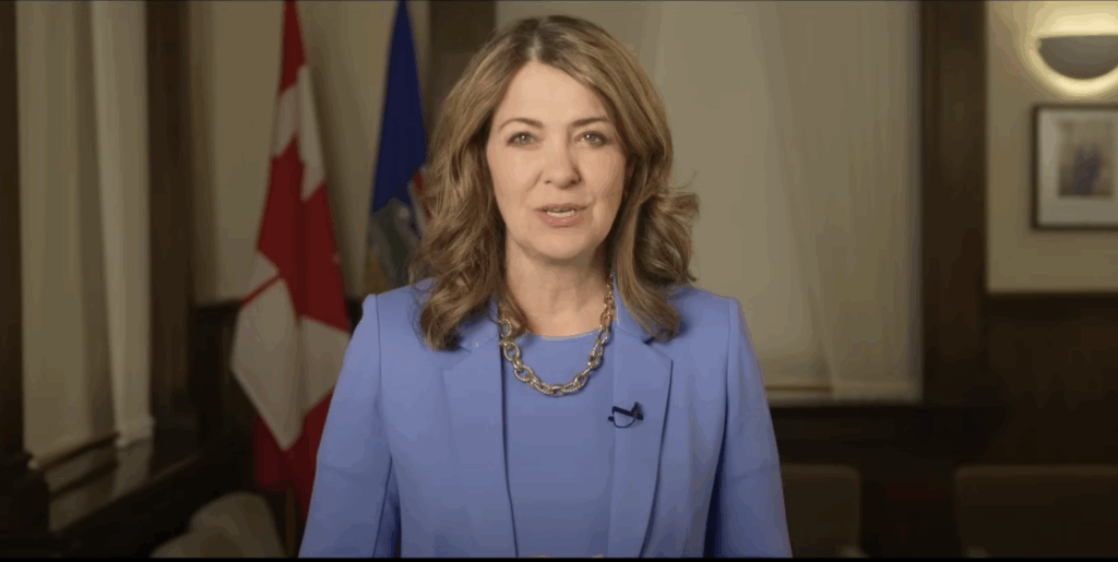 Danielle Smith stands in front of Canada and Alberta flags