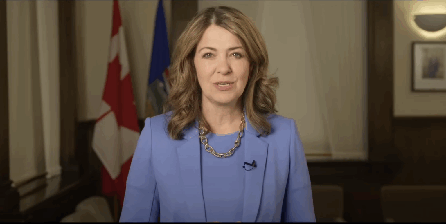 Danielle Smith stands in front of Canada and Alberta flags