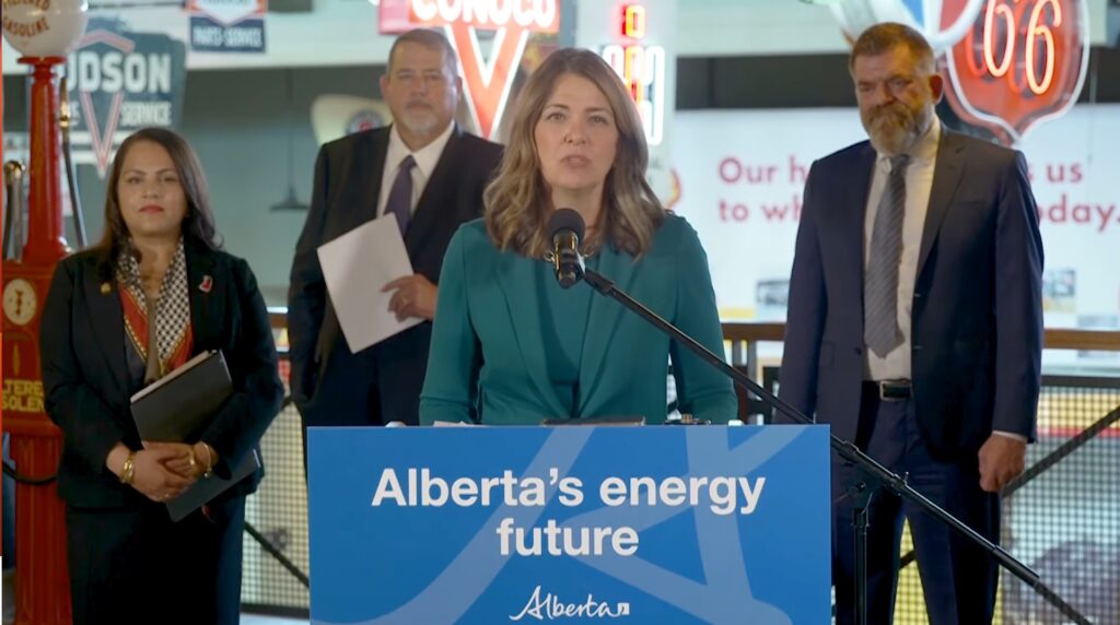 A woman stands in front of a blue podium that says 'Alberta's energy future'