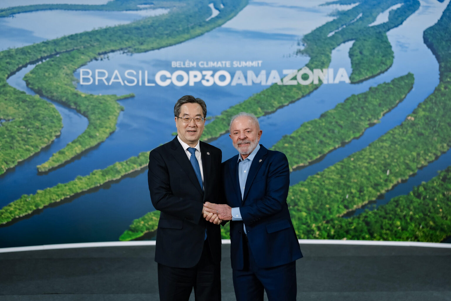 World leaders from Brazil and China shake hands in front of a COP30 banner