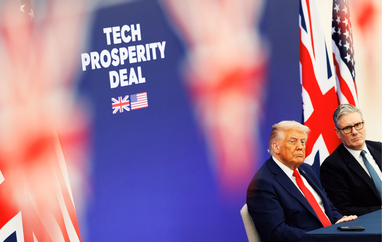 US President Donald Trump and UK Prime Minister Keir Starmer sit in the lower right in front of UK and US flags and a backdrop that says "Tech Prosperity Deal."