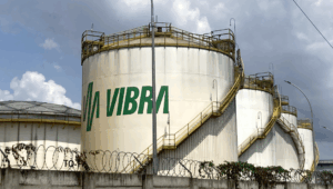 A line of giant white fuel silos, one behind the other receding to the right. The Vibra logo painted in green is visible on the front silo.