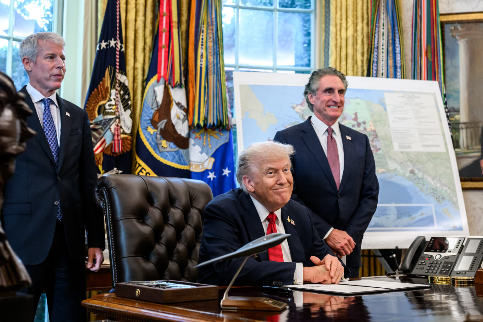 President Donald Trump, flanked by Secretary of Energy Chris Wright and Secretary of the Interior Doug Burgum, signs an Executive Order approving the Ambler Road Project in Alaska, Monday, October 6, 2025, in the Oval Office.
