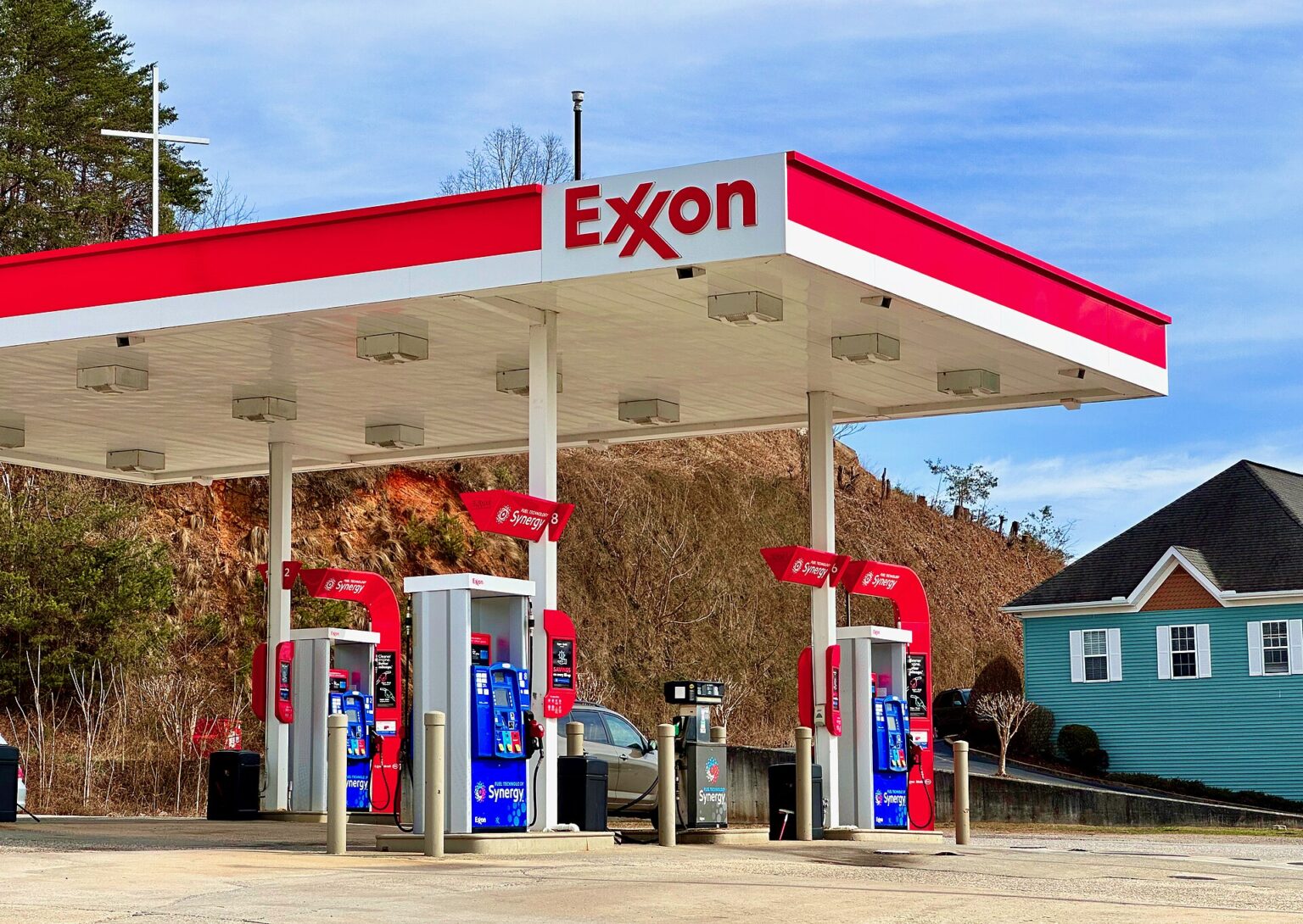 An ExxonMobil gas station in Hiawassee, Georgia, with a blue house in the background.