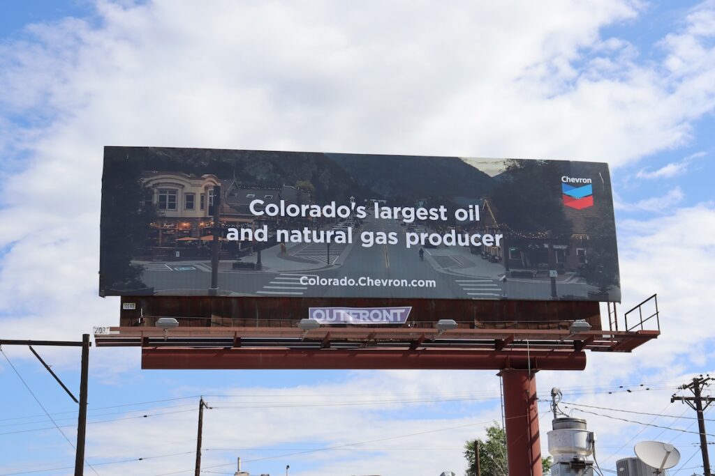 Billboard of homes lit up at night, reading 'Colorado's largest oil and natural gas producer. Chevron'