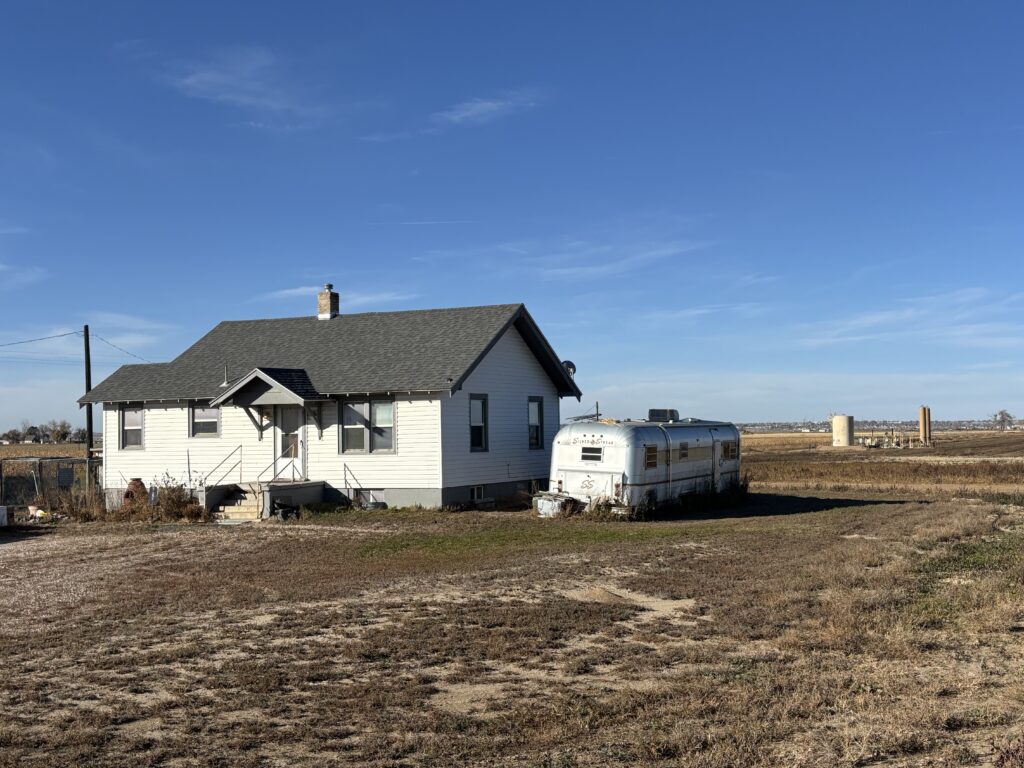A shut-in gas well looms behind a home near LaSalle, Colorado.