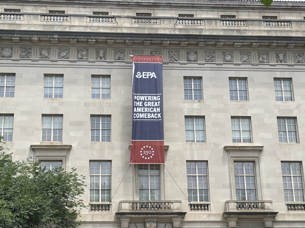 A red, white, and blue banner with the EPA logo and U.S. 250th anniversary that reads 'Powering the Great American Comeback' on the outside of the EPA headquarters in Washington, D.C.