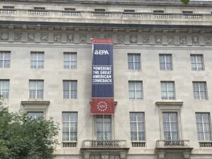 A red, white, and blue banner with the EPA logo and U.S. 250th anniversary that reads 'Powering the Great American Comeback' on the outside of the EPA headquarters in Washington, D.C.